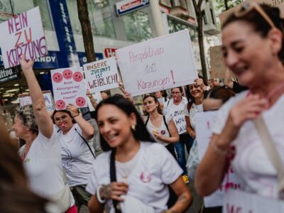 Frauen protestieren mit Schildern gegen die Kürzungen